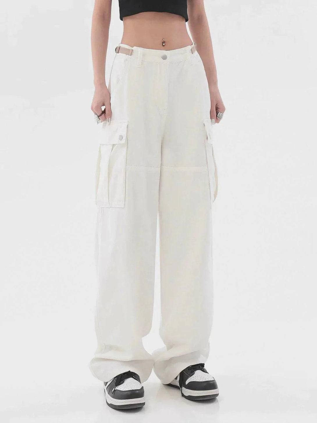 Model in white TALISHKO cargo pants, styled with a black crop top and sneakers.
