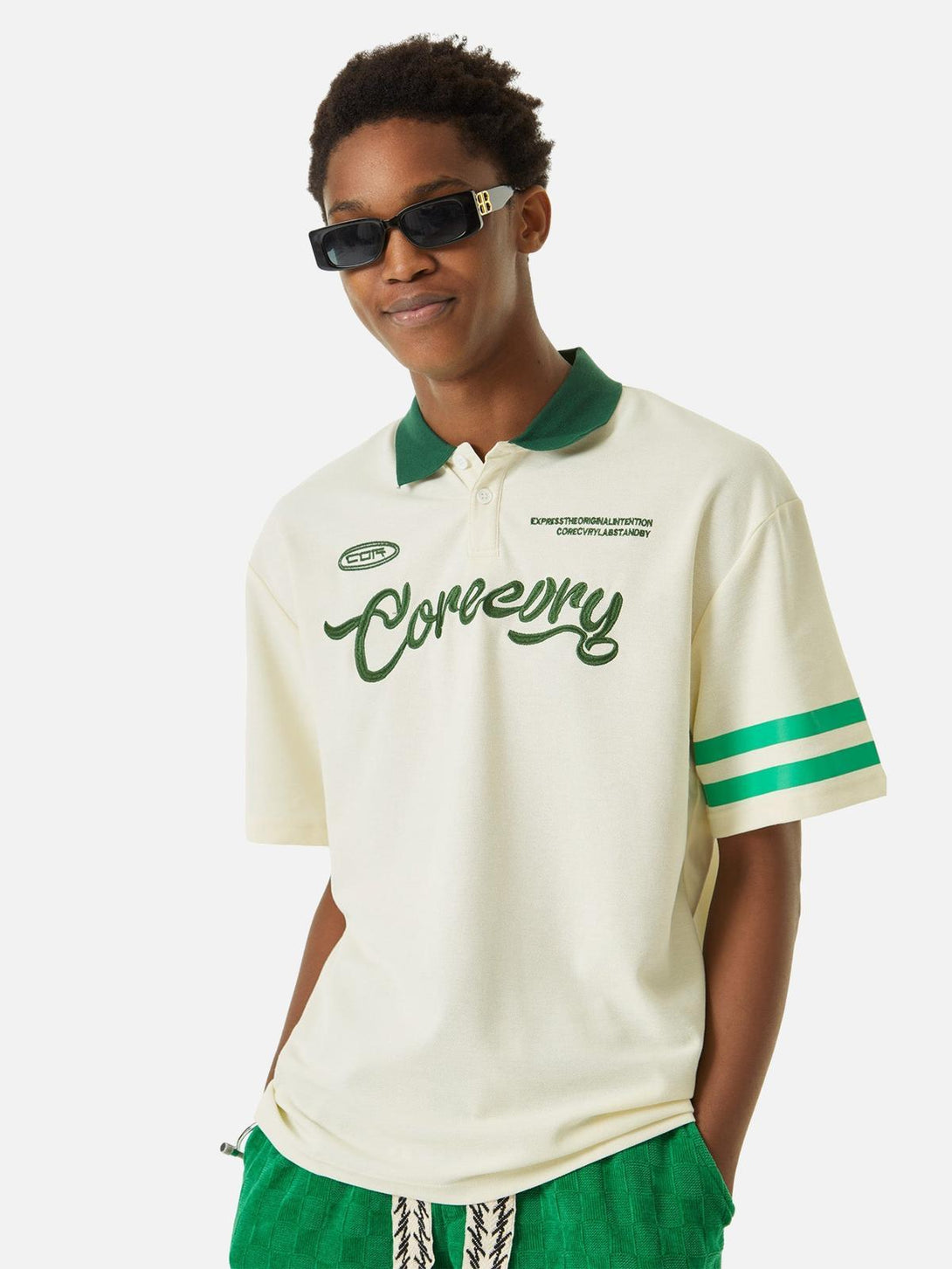 Model wearing a beige polo shirt with green accents by TALISHKO, showcasing casual style.