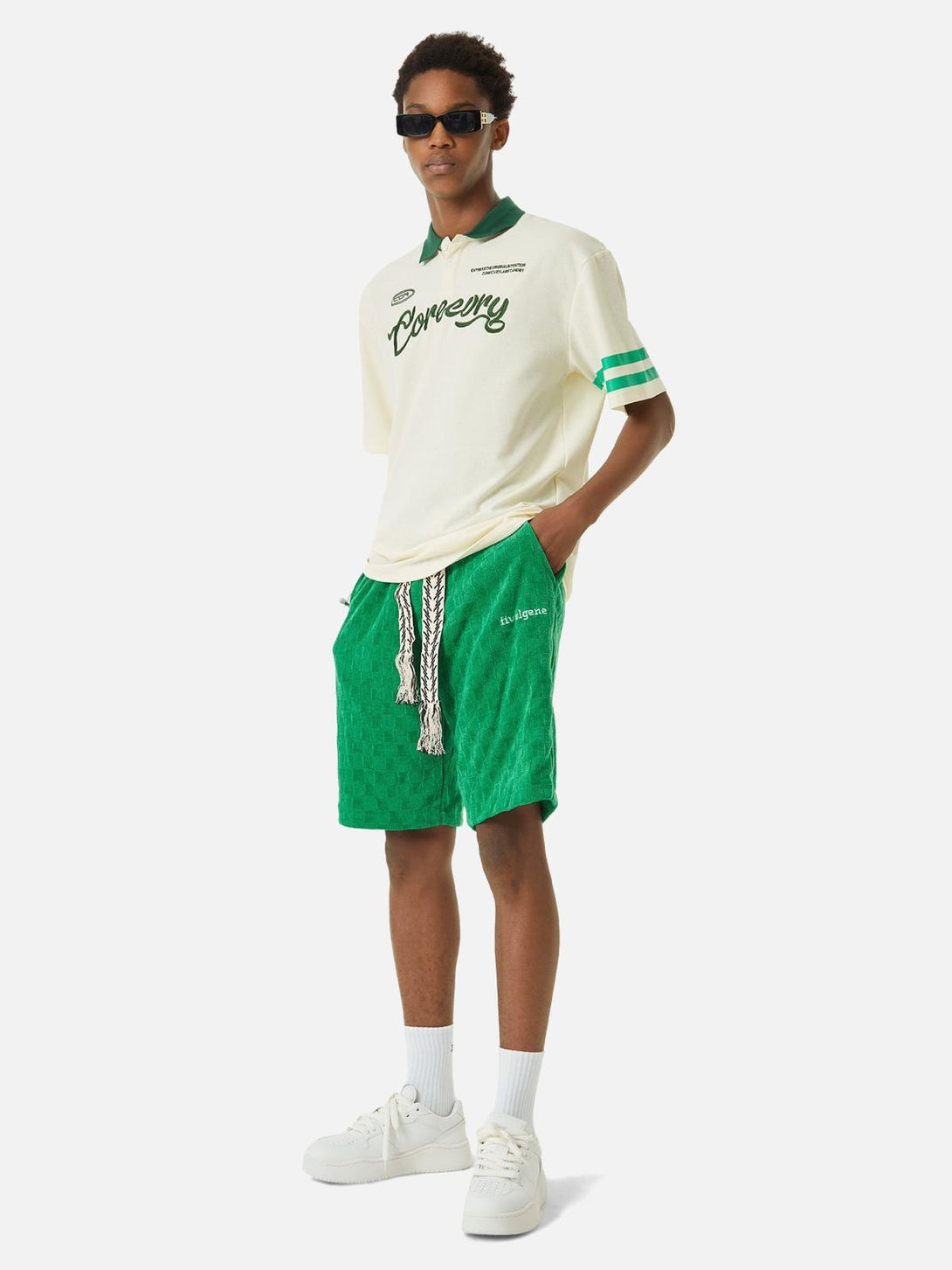 Model in a beige polo shirt with green accents and shorts by TALISHKO, embodying urban style.