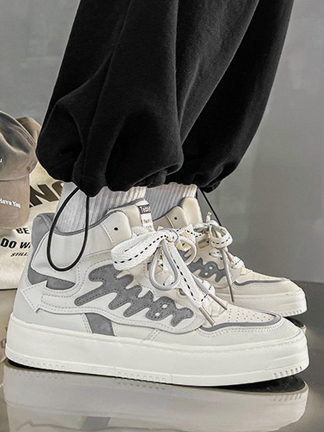 TALISHKO high-top skate shoes in gray with bold side design, styled with casual black pants.