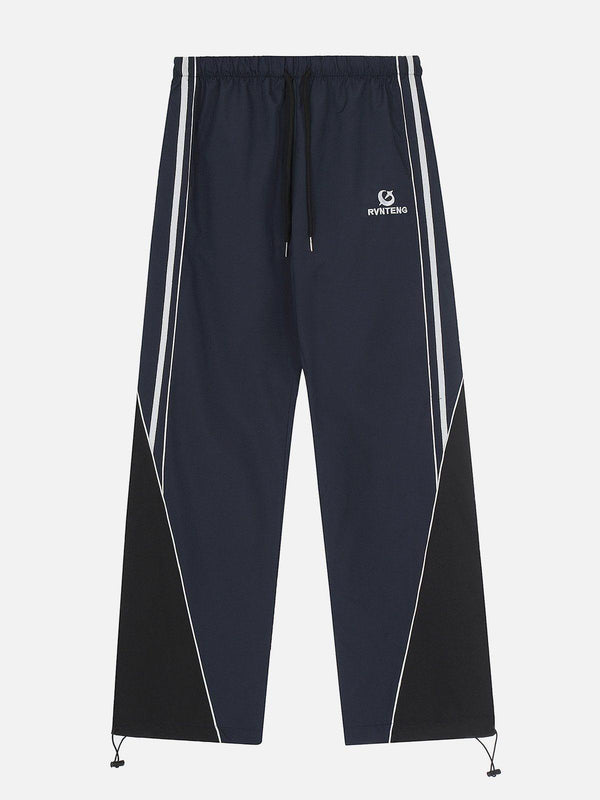 Front view of blue patchwork tapered sweatpants by TALISHKO, featuring sporty white stripes.