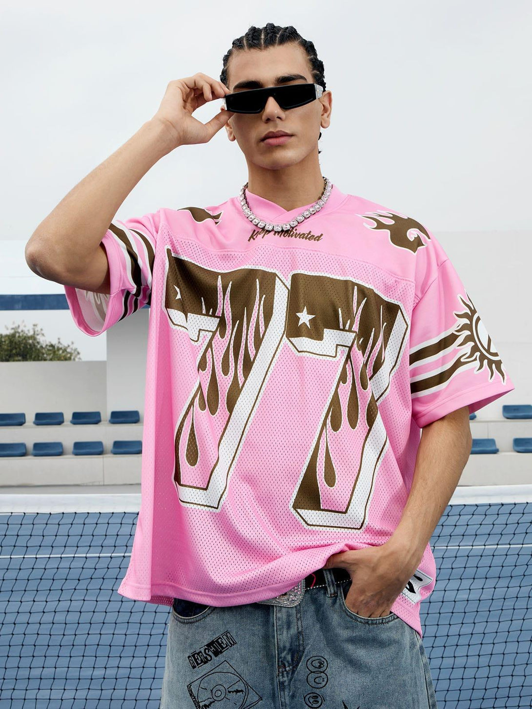 Model wearing pink flame print jersey T-shirt by TALISHKO, styled with sunglasses and denim.