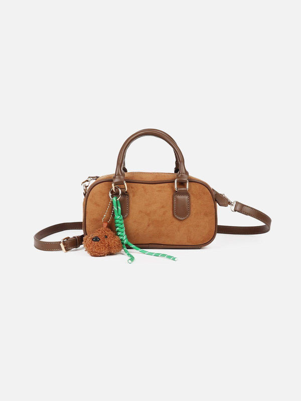 Front view of a brown suede bag by TALISHKO with plush dog charm and green accents.