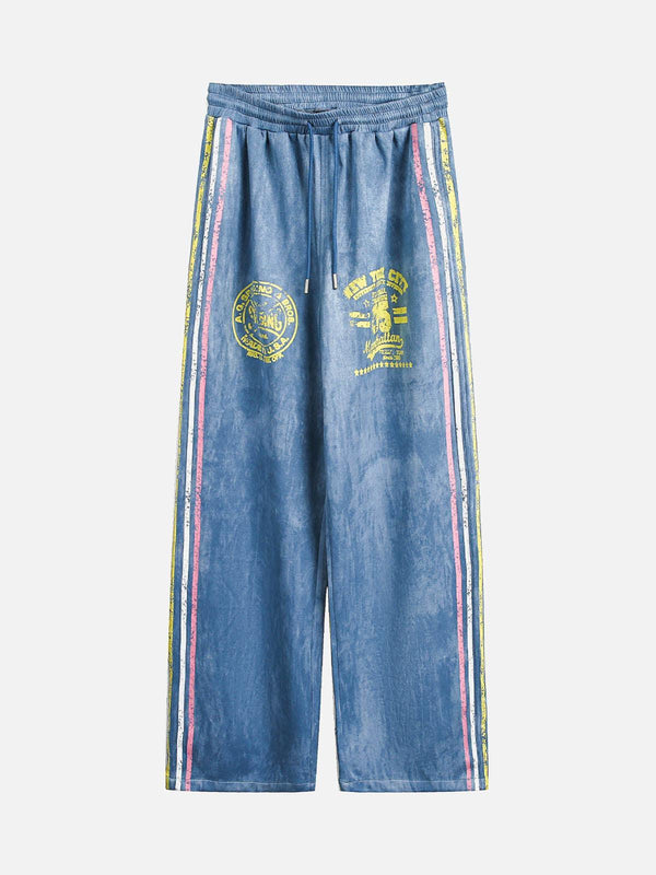 Front view of blue TALISHKO track pants with retro contrast stripes and yellow graphics.