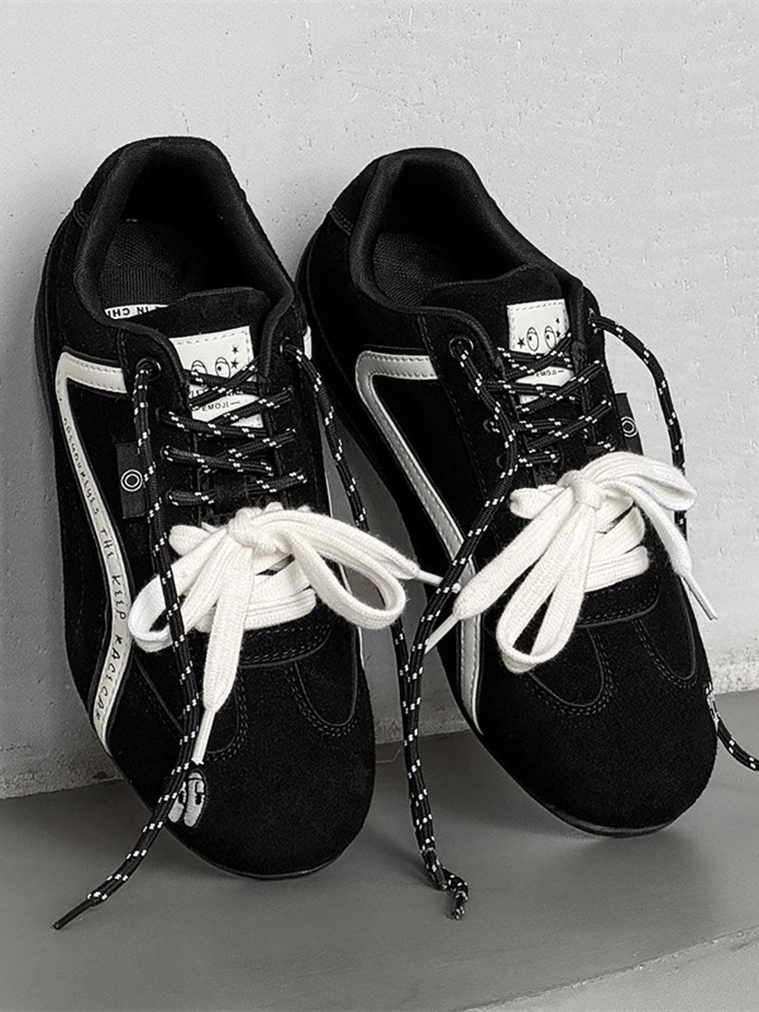 Black suede lace-up sneakers by TALISHKO, featuring playful embroidery and mixed laces.