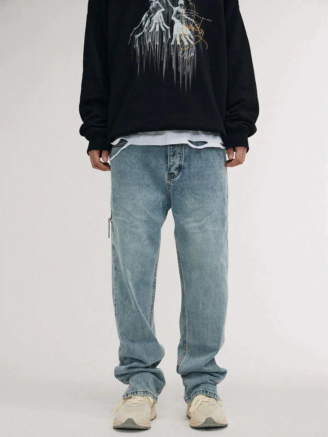 Model in blue vintage jeans and graphic sweatshirt, showcasing TALISHKO's relaxed style.
