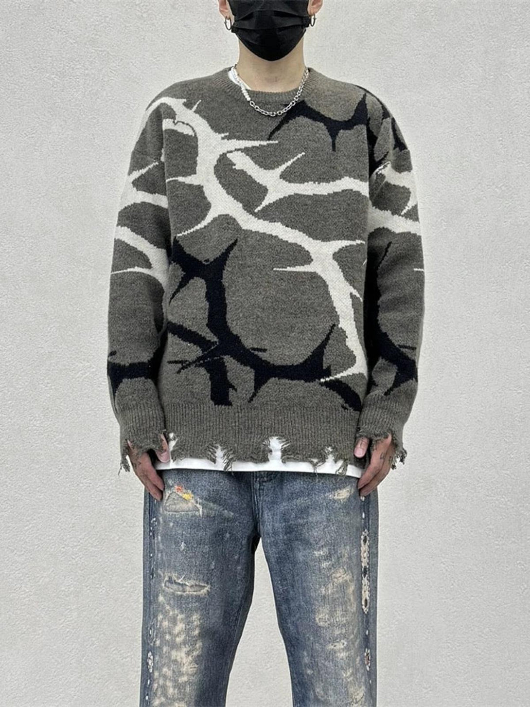 Model wearing a TALISHKO thorn-patterned sweater with distressed edges, paired with faded jeans.