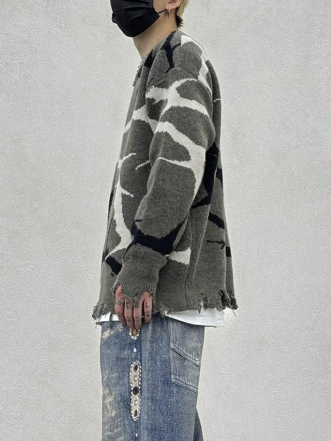 Side view of TALISHKO thorn-patterned sweater with distressed edges, paired with denim.