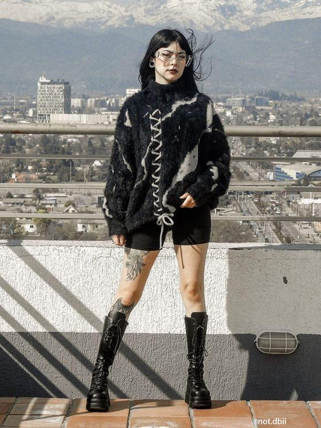 Model wearing TALISHKO's tie-dye bandage turtleneck sweater, styled with boots and shorts.