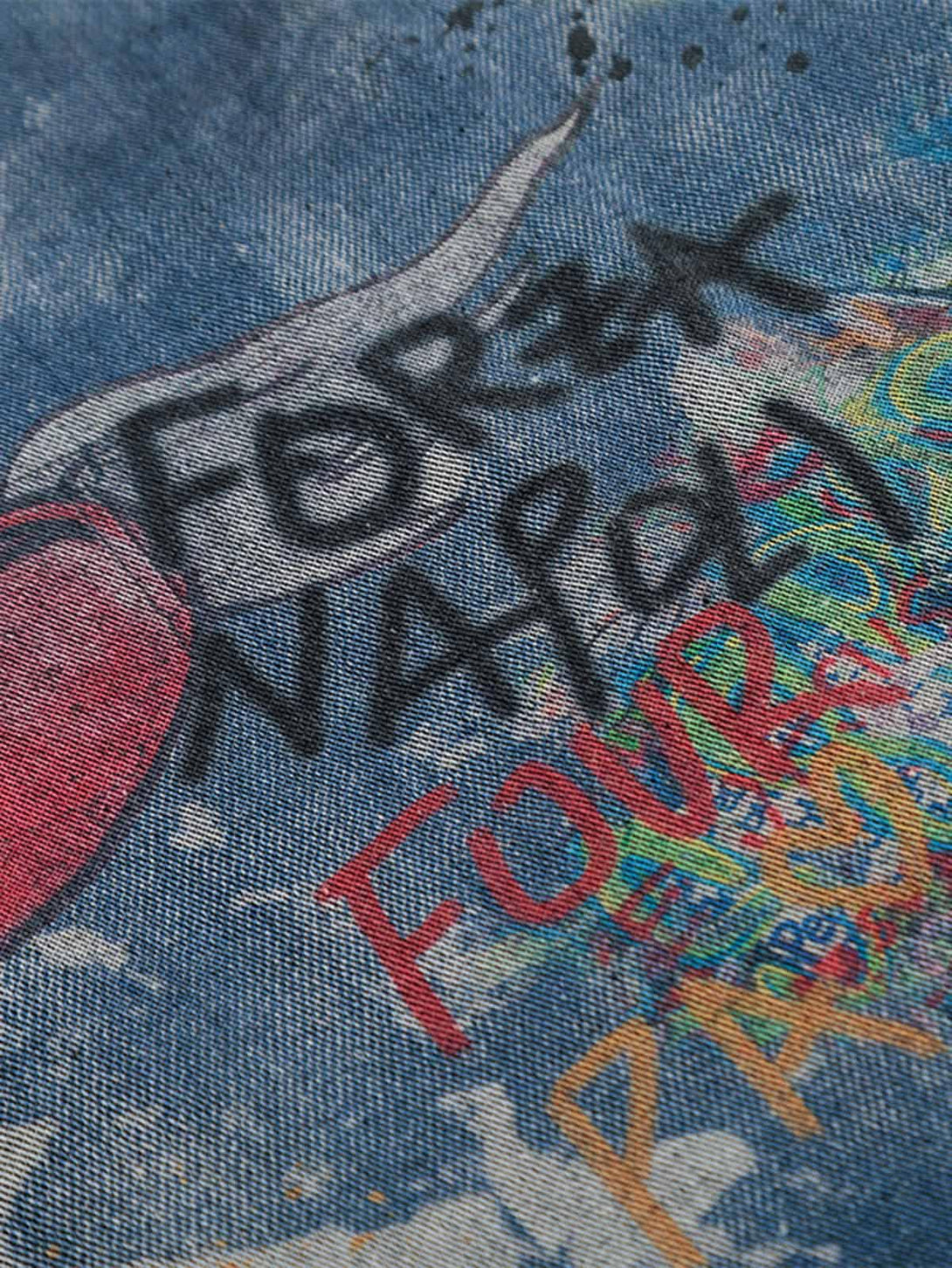 A detailed view of graffiti-inspired patterns on a tie-dye denim polo by TALISHKO, highlighting its artistic design.