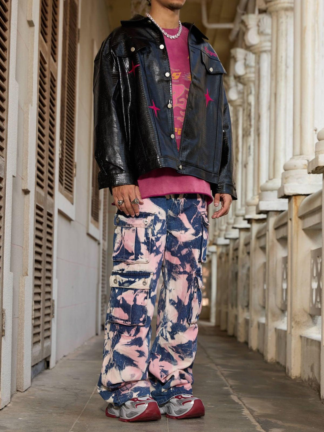 Model in TALISHKO tie-dye camouflage cargo jeans, paired with a black jacket and pink shirt.