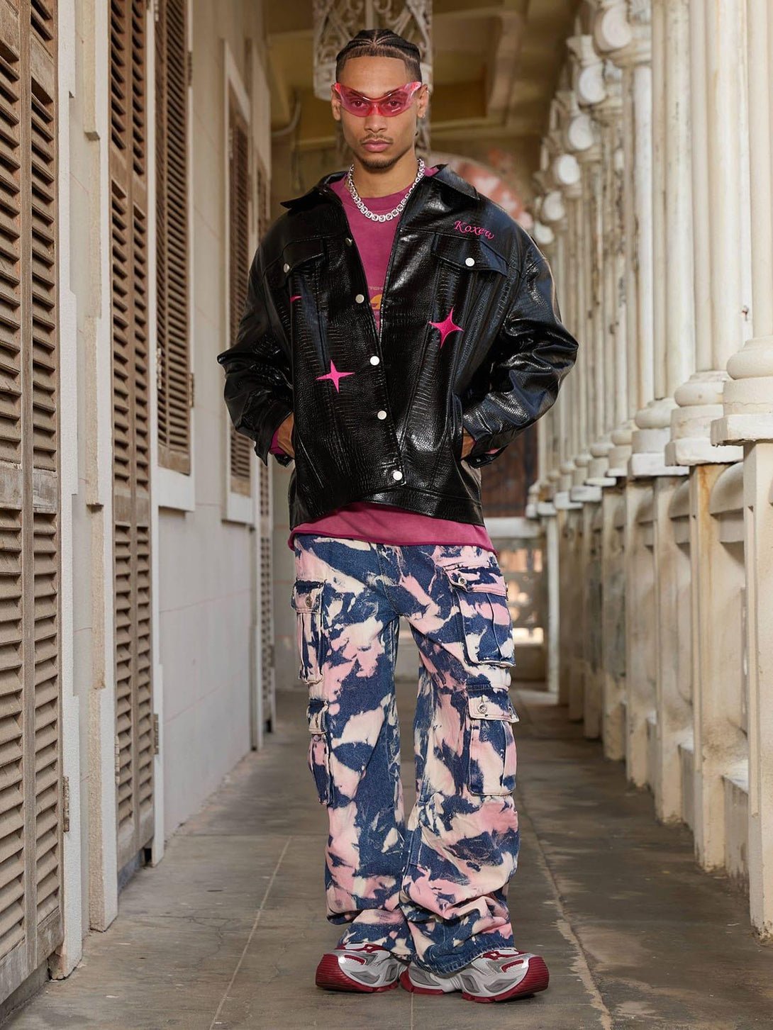 Model showcasing TALISHKO tie-dye camouflage cargo jeans with a black jacket and unique style.