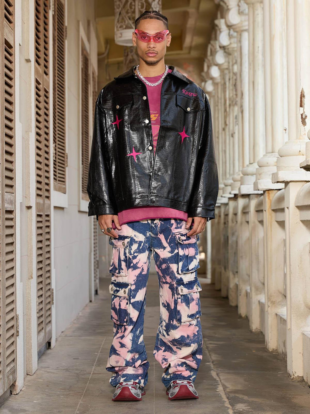 Model wearing TALISHKO's bold tie-dye camouflage cargo jeans with a black jacket and pink accents.