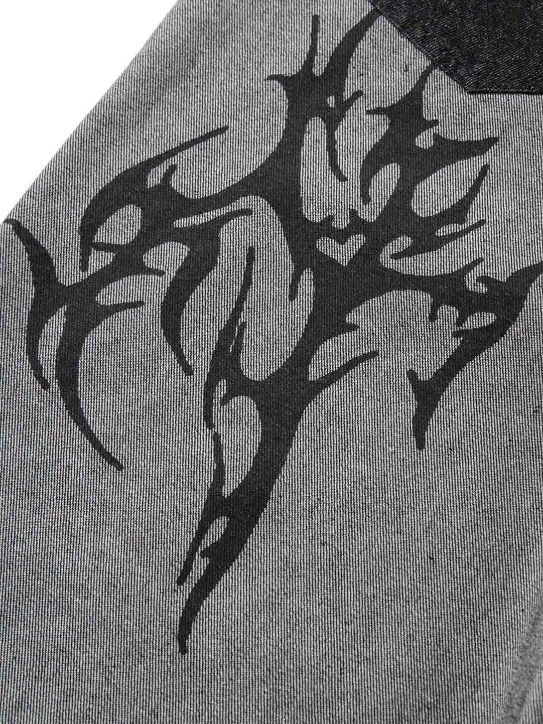 A tight crop highlighting the tribal flame print on TALISHKO's gray baggy jeans.