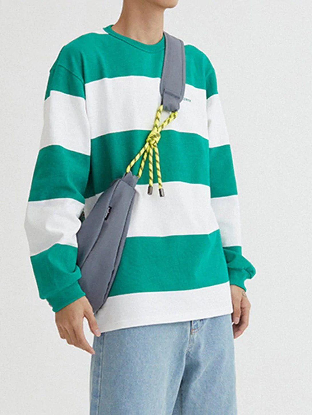 Model wearing a striped sweatshirt with a gray TALISHKO crossbody bag featuring yellow rope accents.