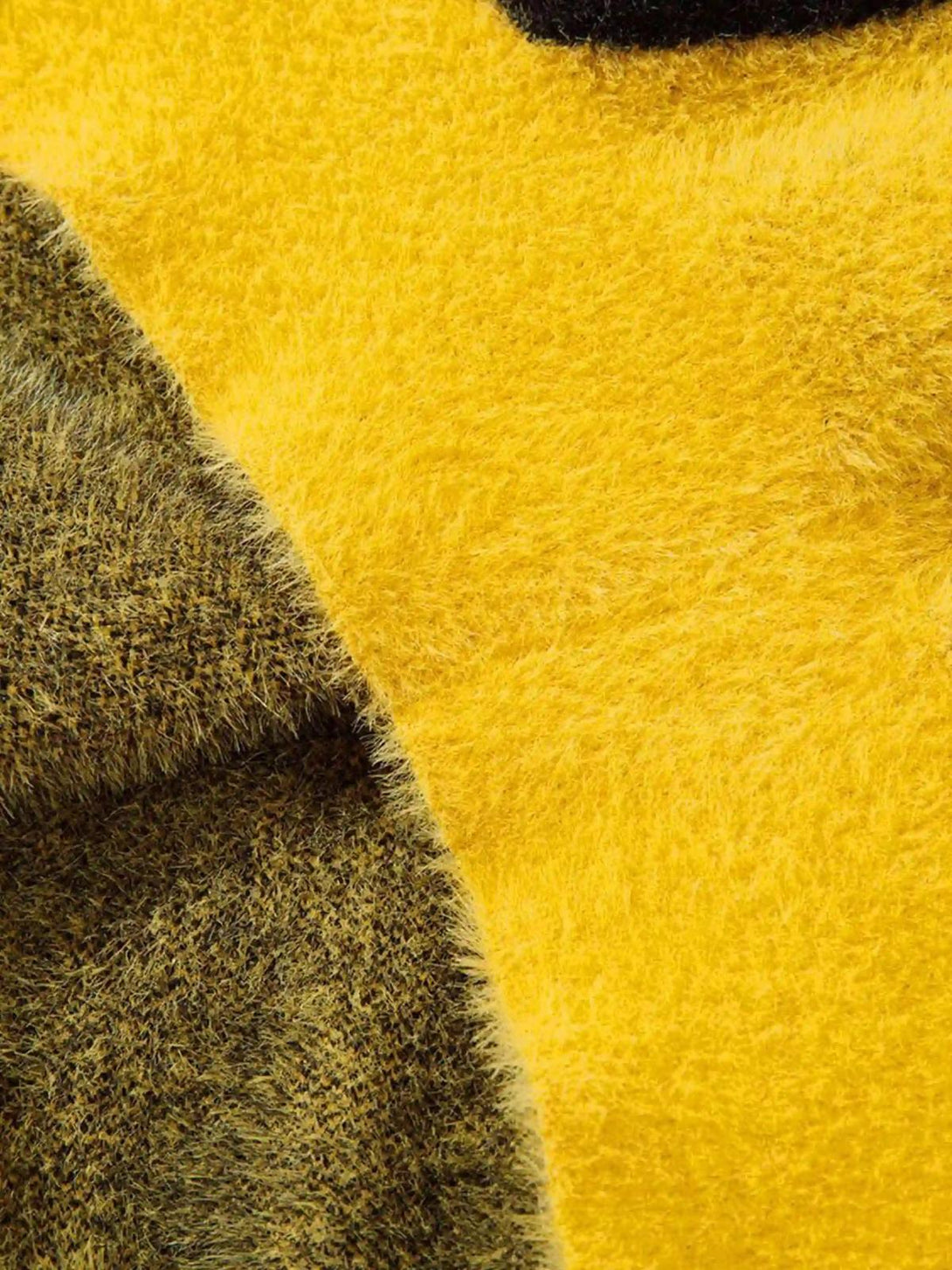A detailed look at the fuzzy texture of a TALISHKO sweater with a bold smiley face design.