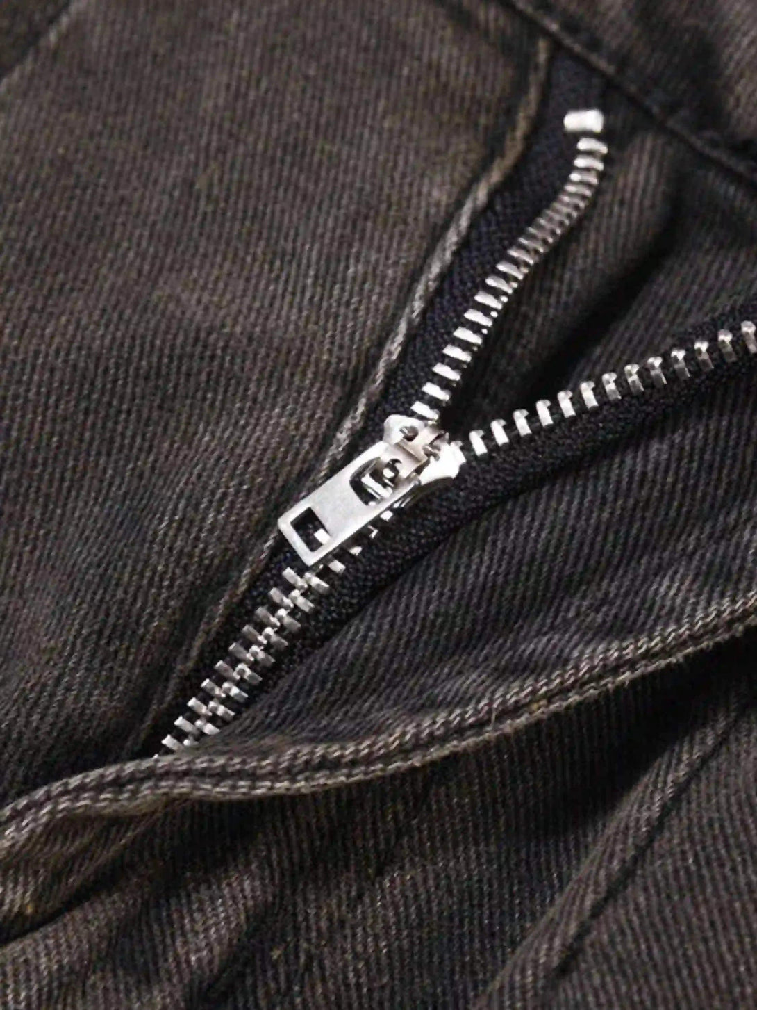 A close-up of TALISHKO vintage denim shorts, showcasing the distressed zipper detail.