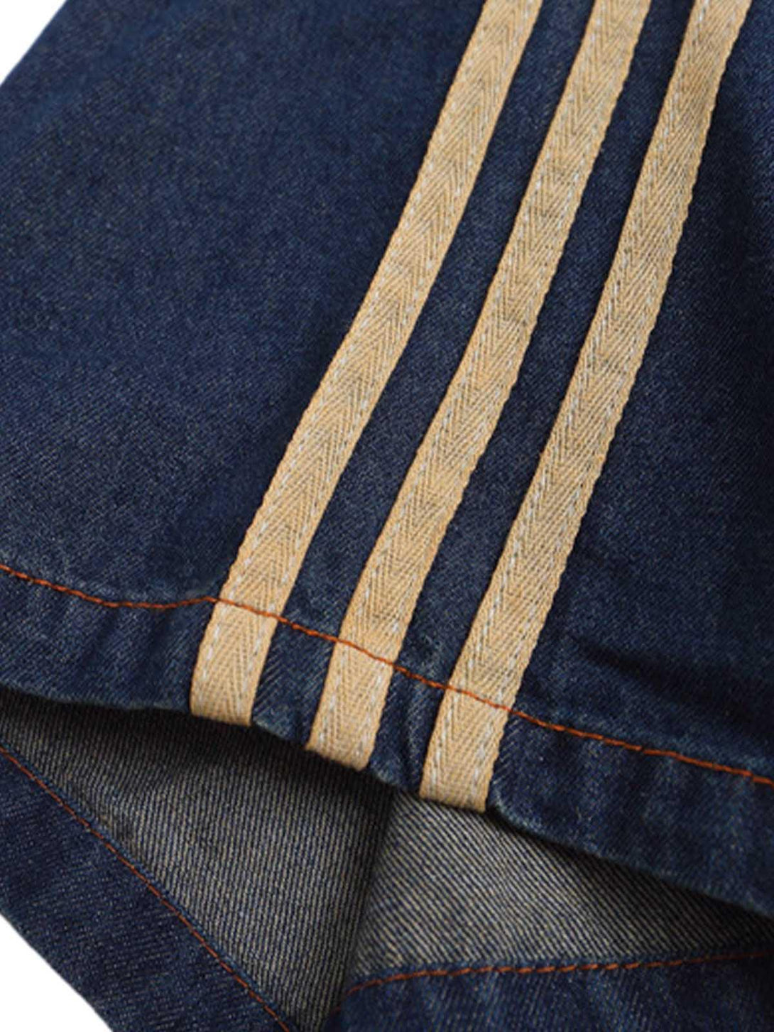 A close-up of TALISHKO's denim T-shirt highlighting the striped sleeve and detailed stitching.