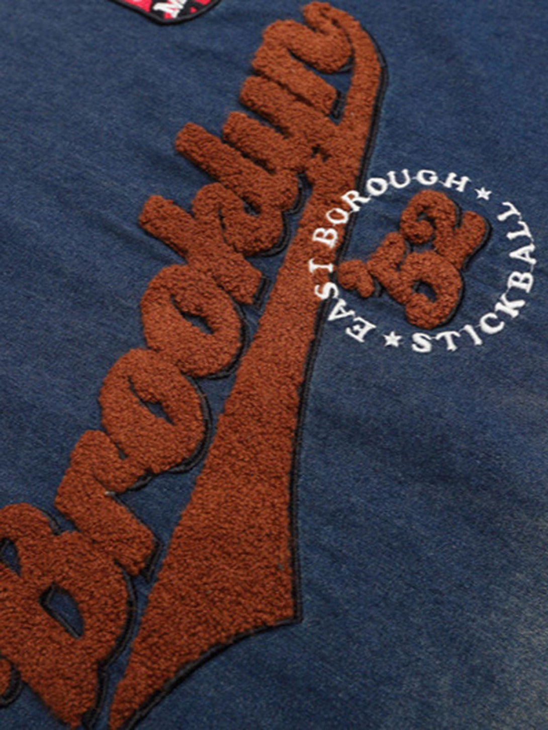 TALISHKO's vintage denim T-shirt's textured logo and stitching detail on washed fabric.