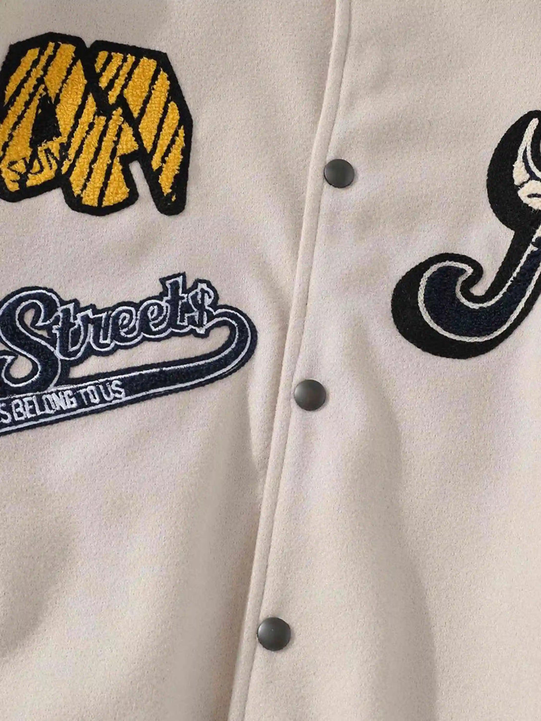 Detailed embroidery on a cream vintage baseball jacket by TALISHKO, highlighting unique style.