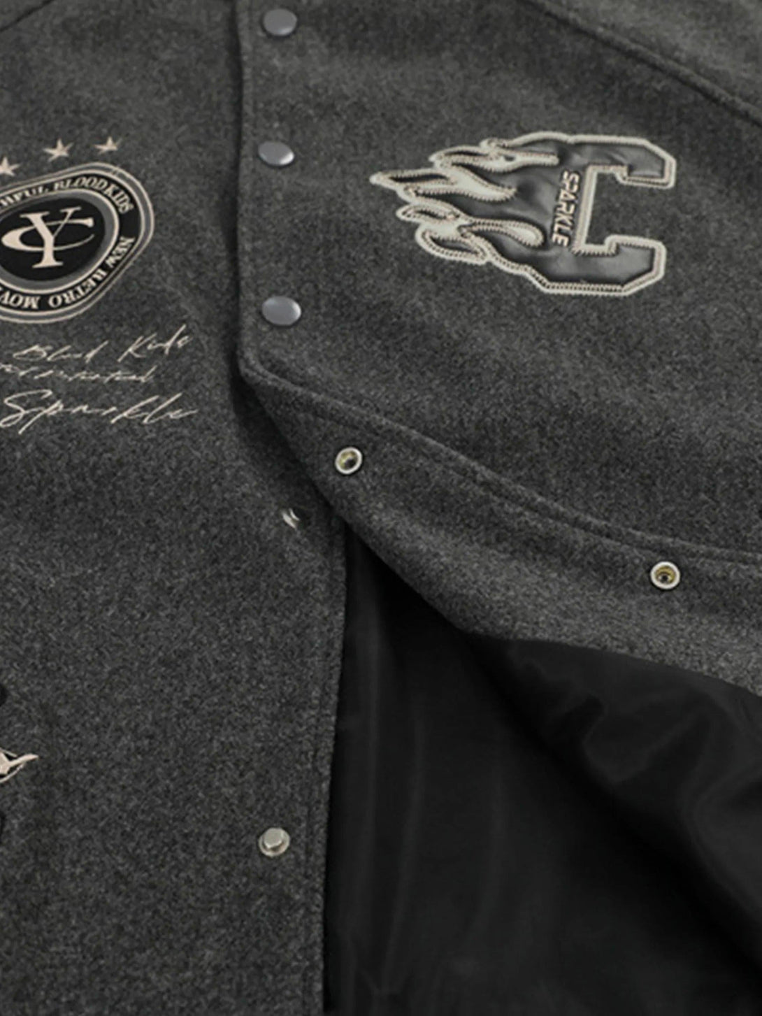 Detailed look at the gray varsity baseball jacket by TALISHKO, highlighting embroidered patches.