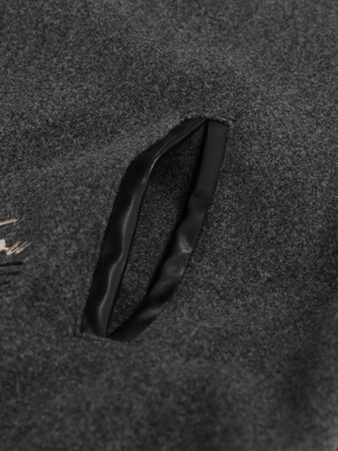 Detailed fabric and stitching of a gray varsity baseball jacket by TALISHKO.