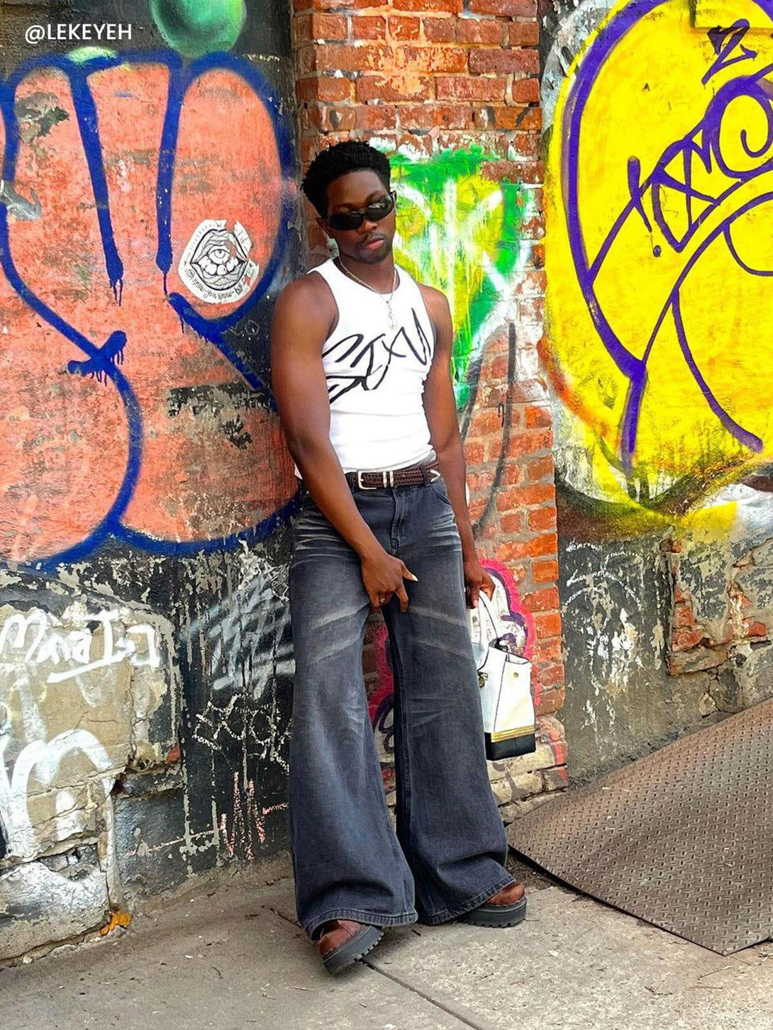 TALISHKO vintage folds loose jeans styled in an urban setting, paired with a white tank top.