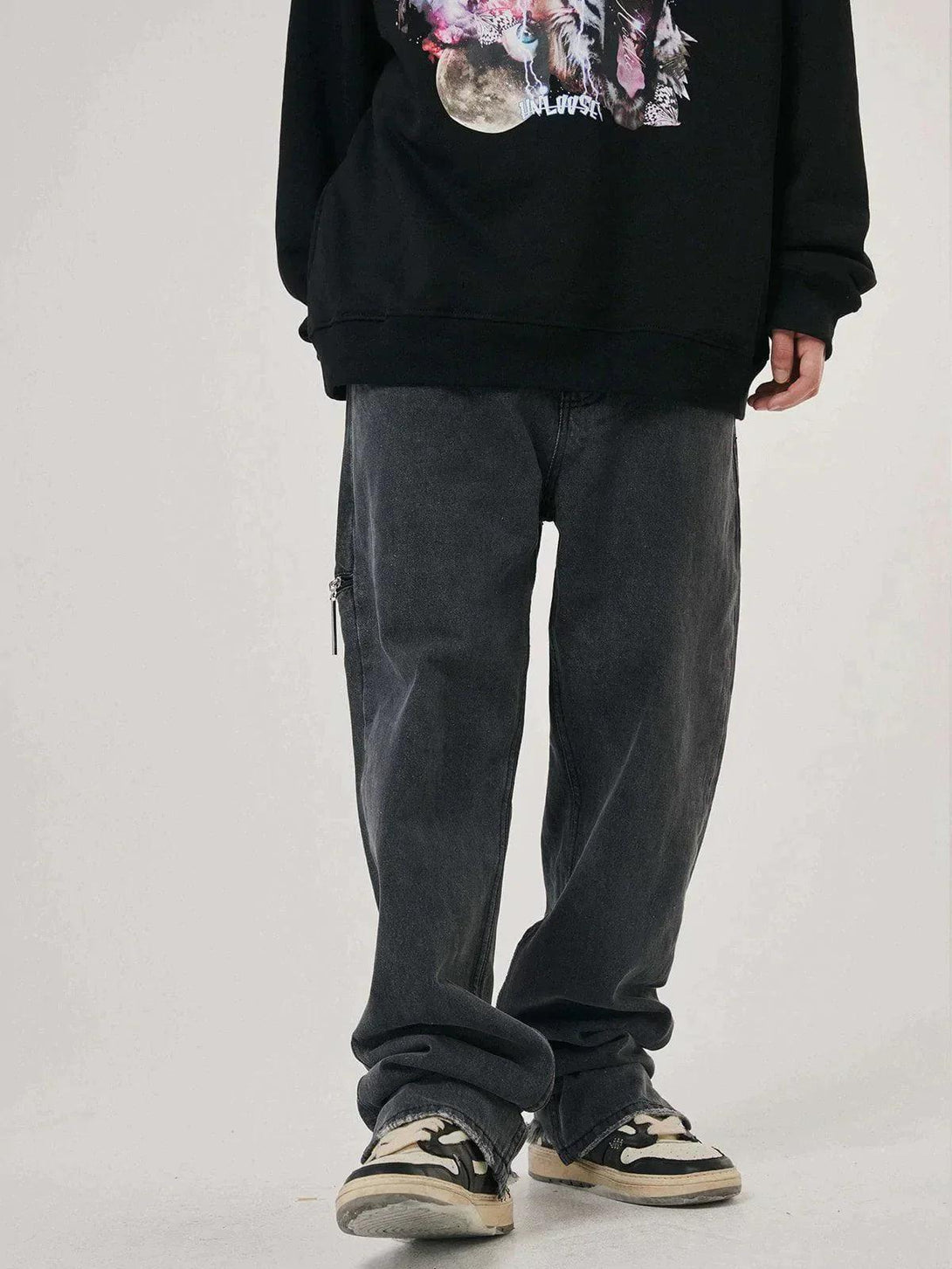 Model wearing vintage frayed wash jeans with a graphic sweatshirt and sneakers by TALISHKO.