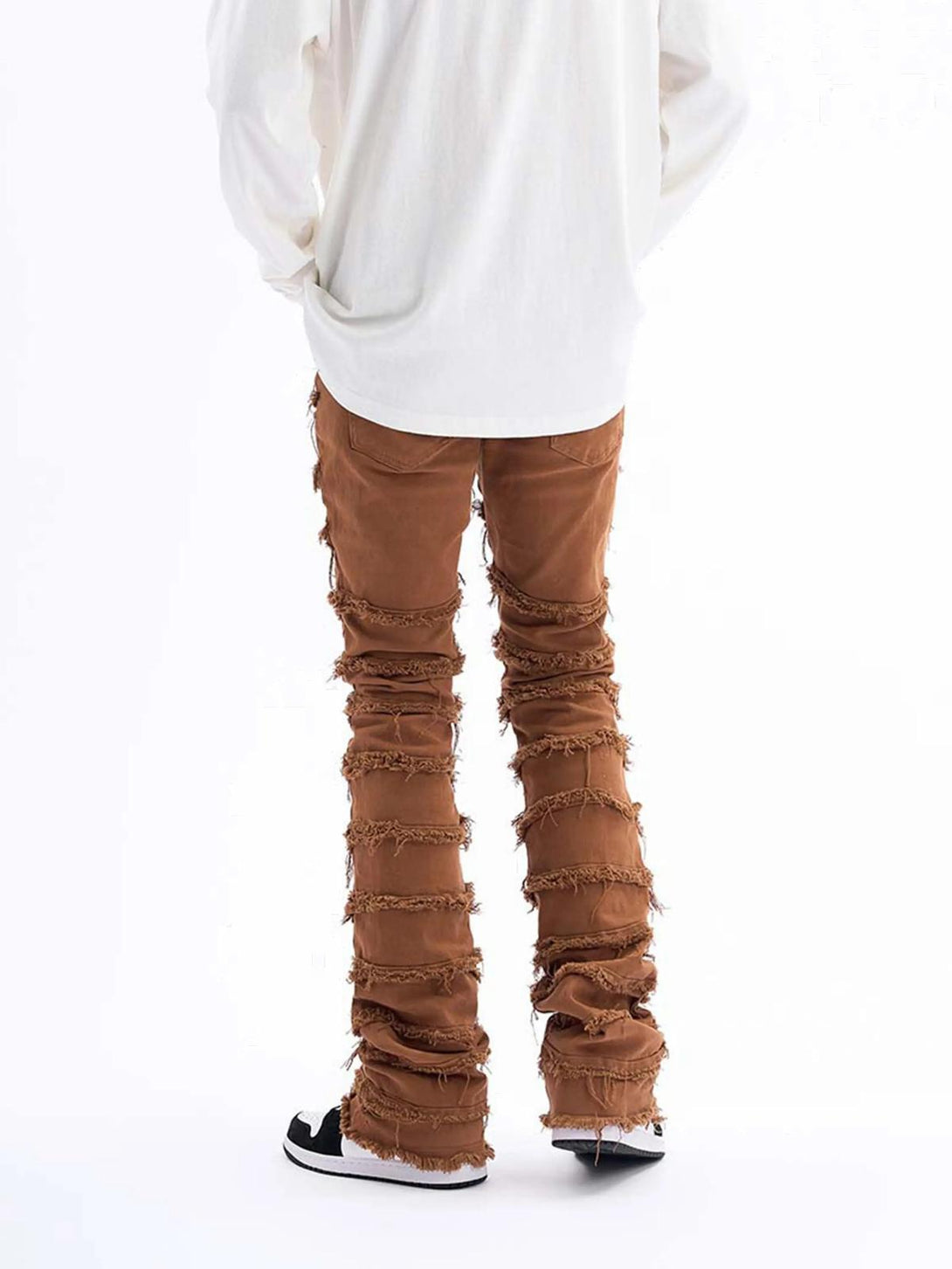 Back view of TALISHKO brown layered jeans showcasing unique raw edge detailing.