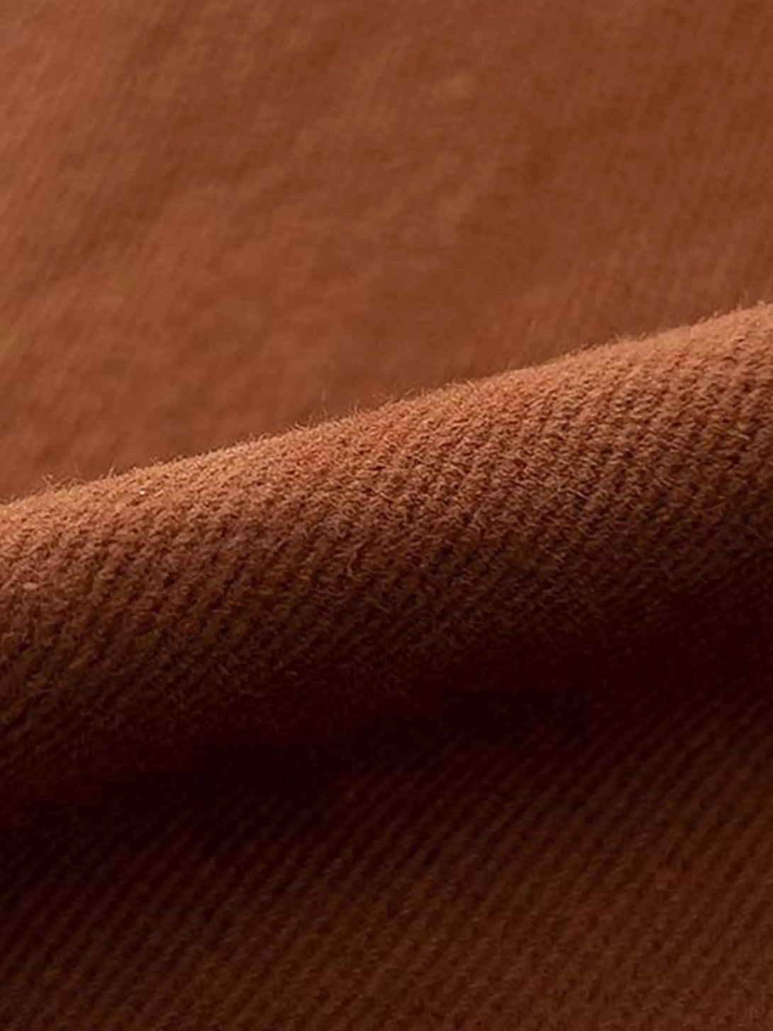 A detailed view of the rich brown texture of TALISHKO's vintage layered slim jeans.