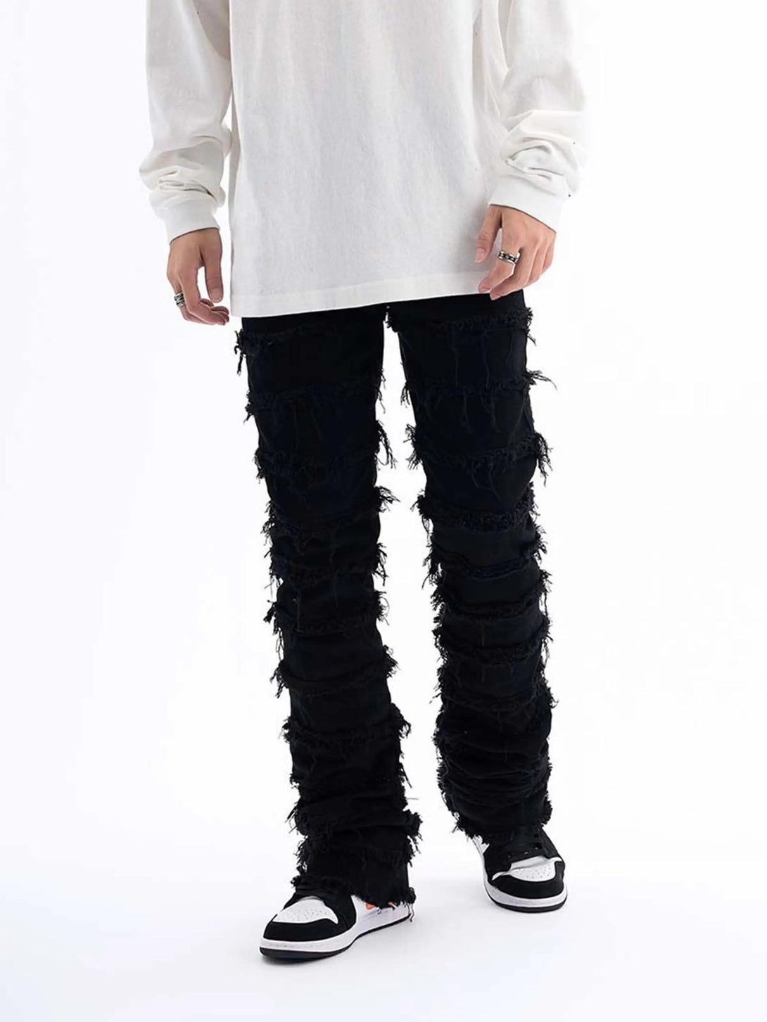 Model wearing TALISHKO vintage layered slim jeans with raw edges, styled with casual sneakers.