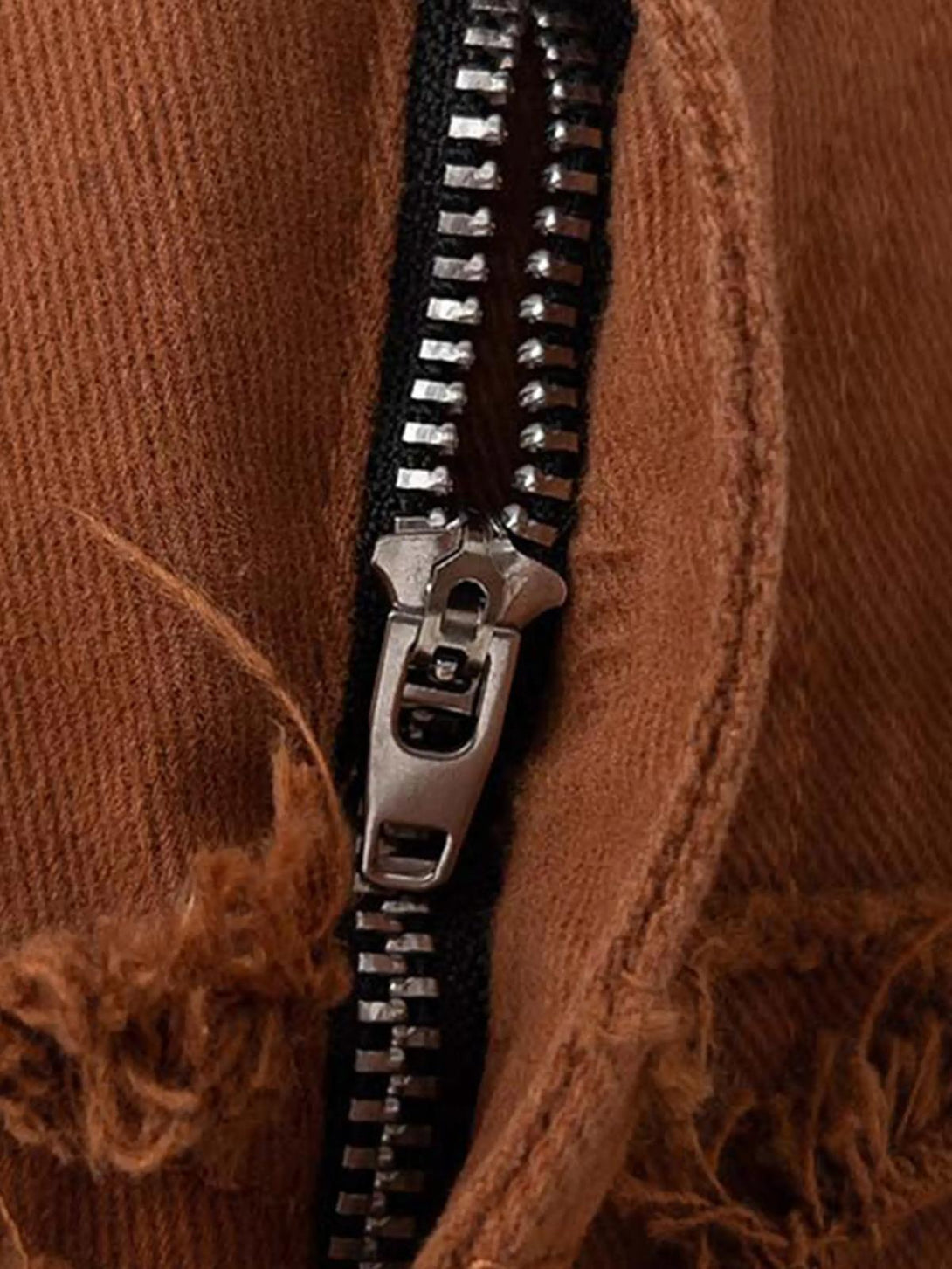 A detailed look at TALISHKO's distressed zipper detail on vintage layered slim jeans.