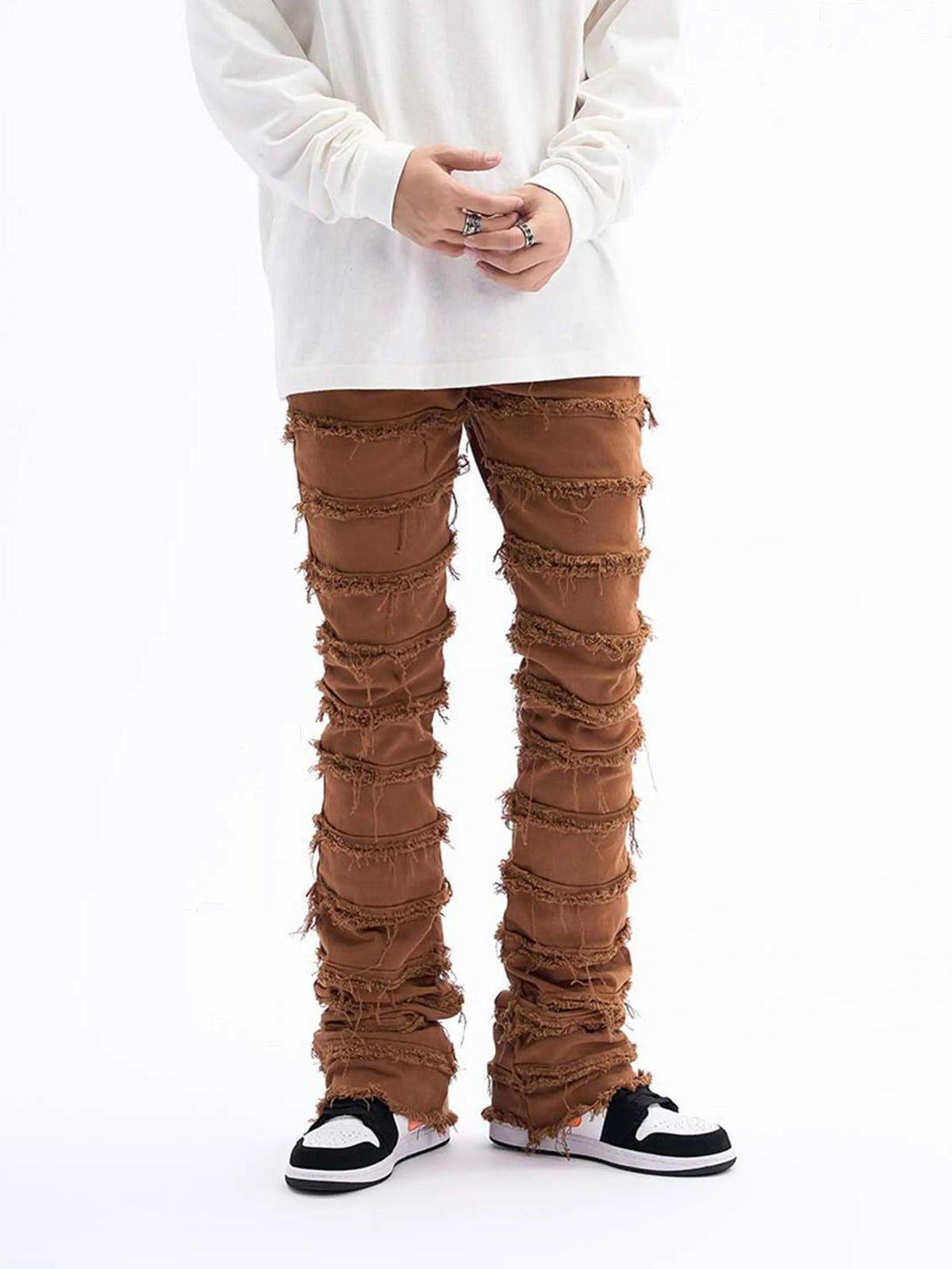 TALISHKO vintage slim jeans with layered raw edges paired with casual sneakers for a trendy look.