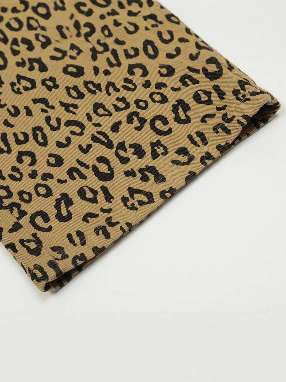 Zoomed-in texture of TALISHKO leopard print pants, showcasing detailed fabric pattern.