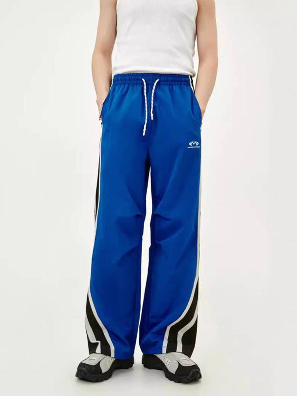Model wearing blue TALISHKO vintage-style sweatpants with black and white side stripes.