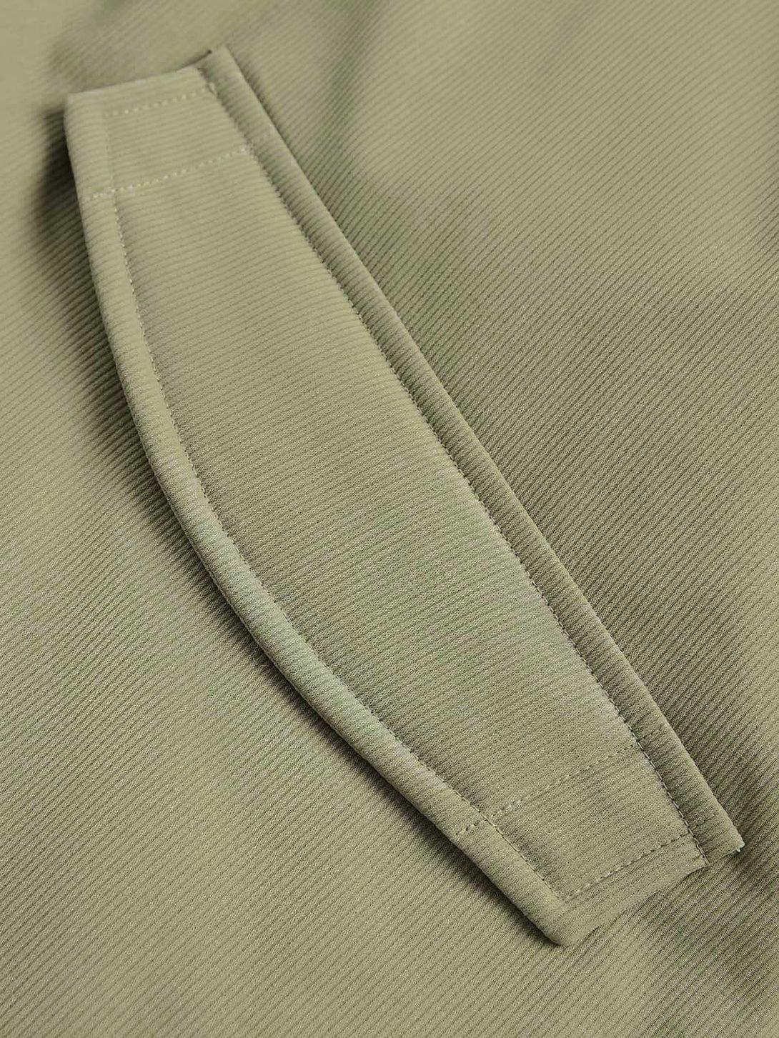 A close-up of the green pocket detail on TALISHKO's vintage oversized pleated jacket.