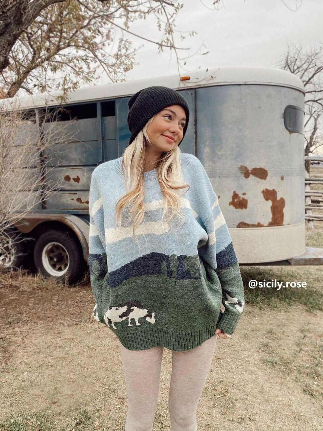 A model wears a cozy vintage-inspired cow pattern sweater by TALISHKO, paired with a black beanie.