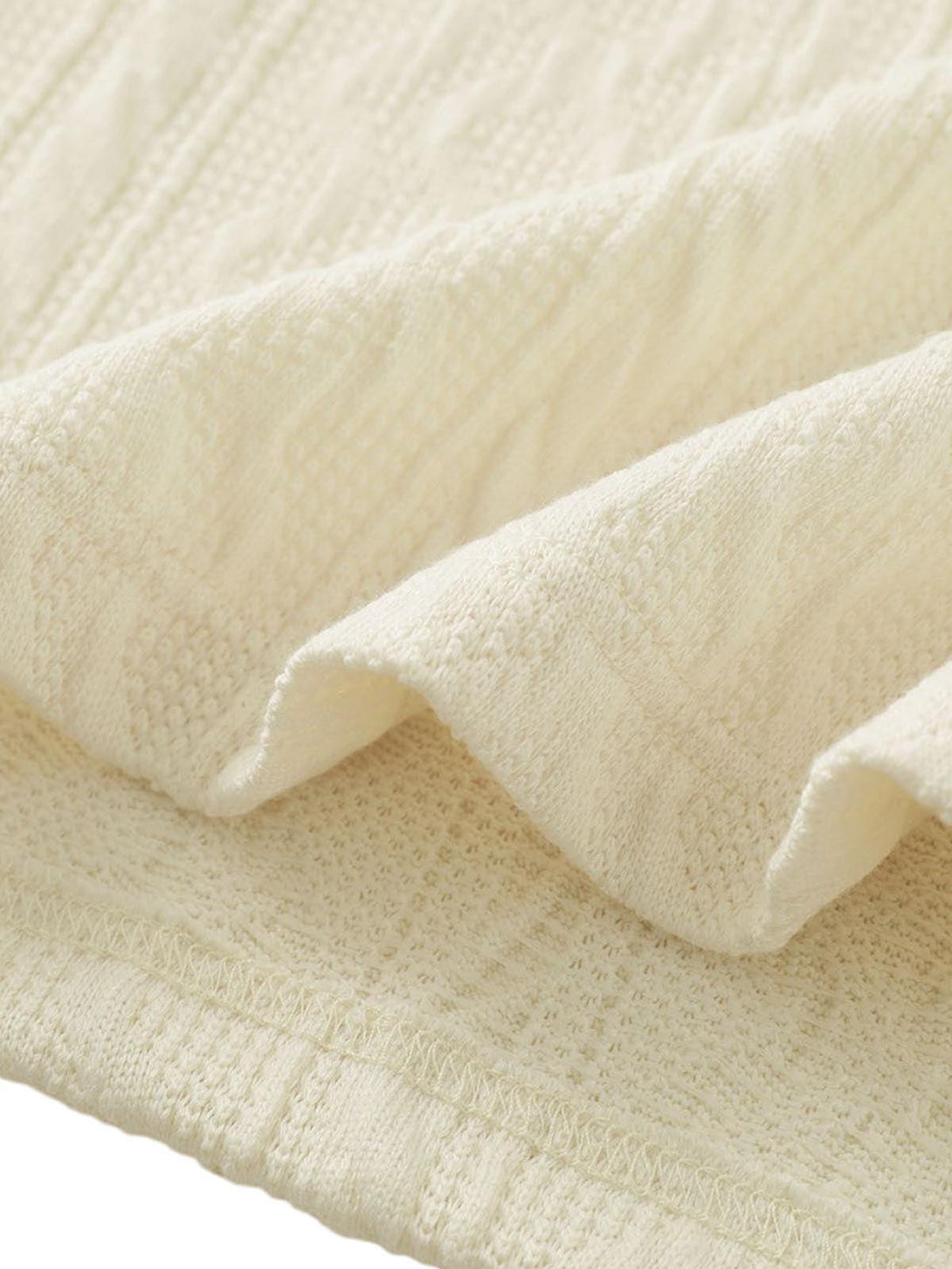 Detailed fabric and texture of a cream knit sweater by TALISHKO, highlighting cozy design.