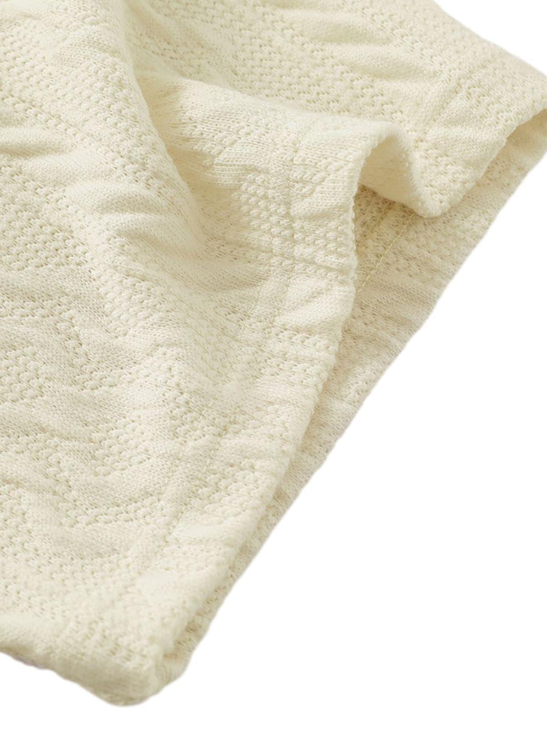 A tight crop highlighting the intricate cable knit texture of a cream sweater by TALISHKO.
