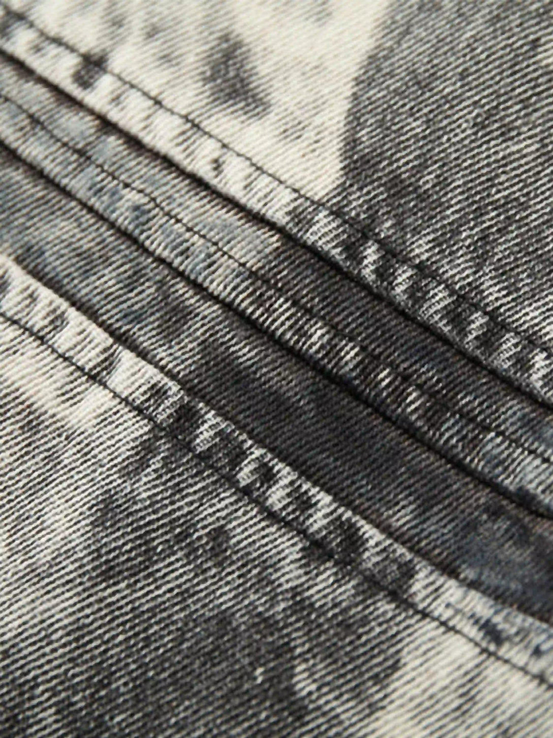 "Zoomed-in texture of TALISHKO's distressed print jacket, highlighting intricate stitching."
