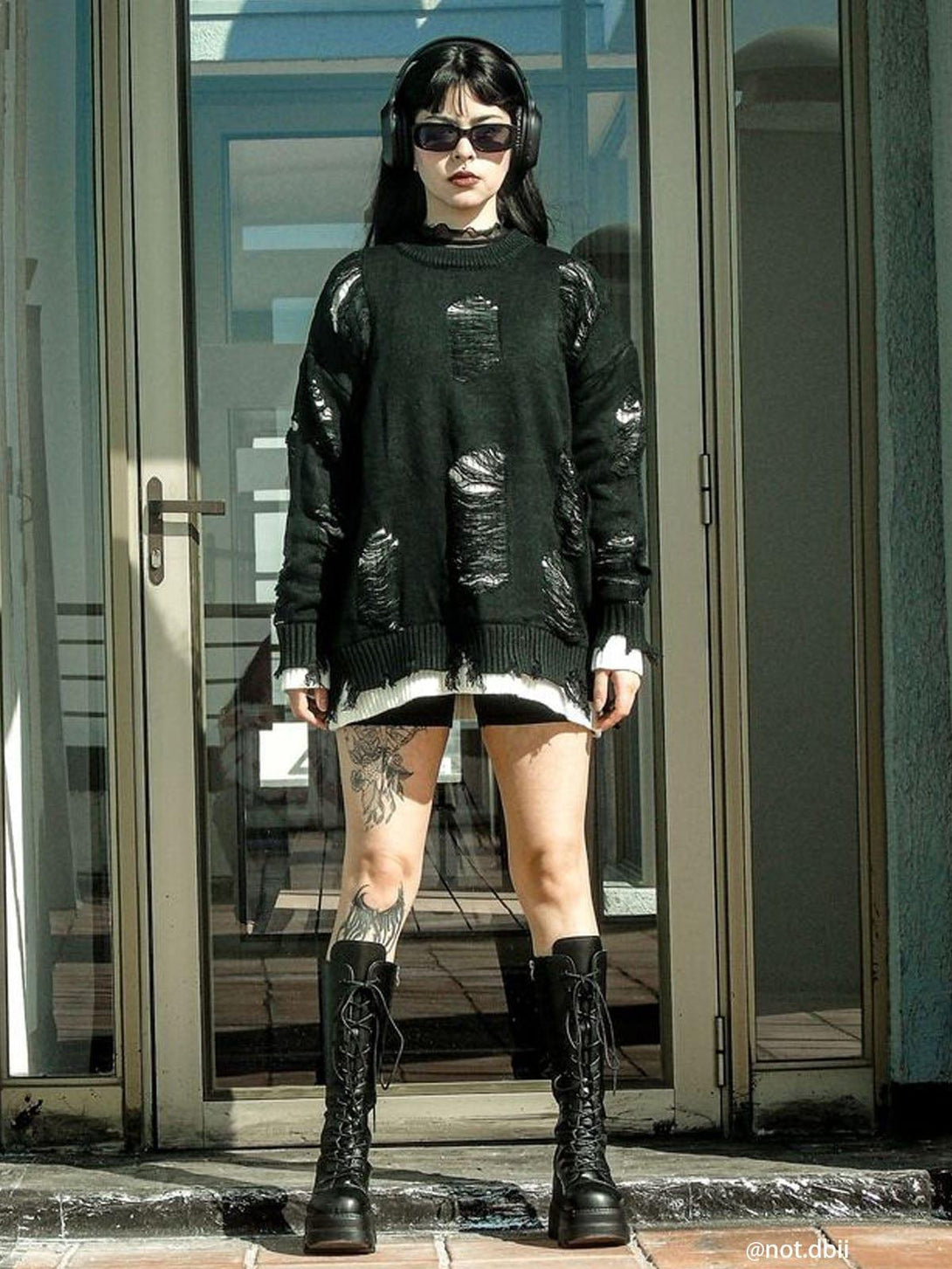 Model wearing a black vintage ripped oversized sweater styled by TALISHKO, paired with tall boots.
