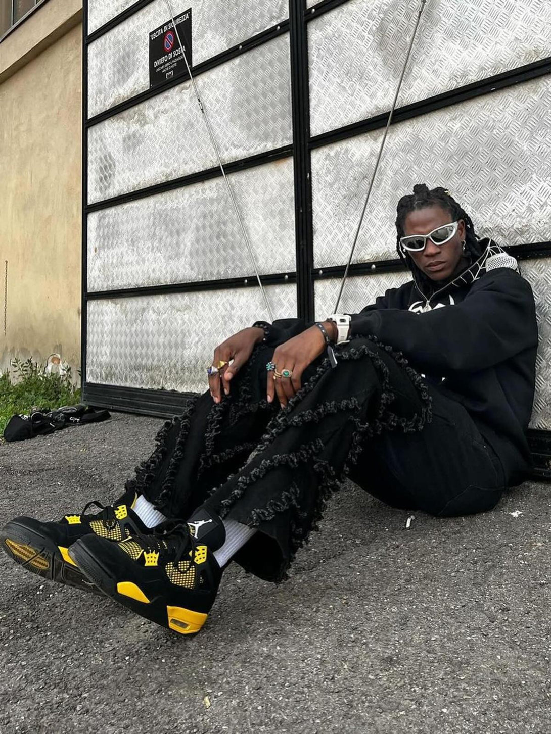 Model wearing TALISHKO's vintage flared jeans with rough edges, styled with sneakers and accessories.