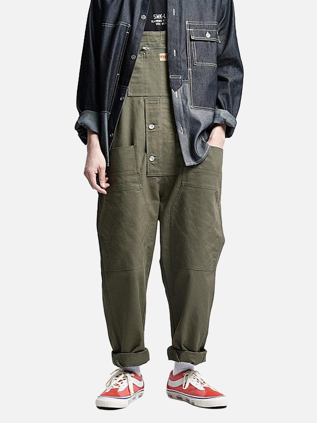 Model wearing TALISHKO vintage men's overalls in olive, paired with a denim jacket and sneakers.