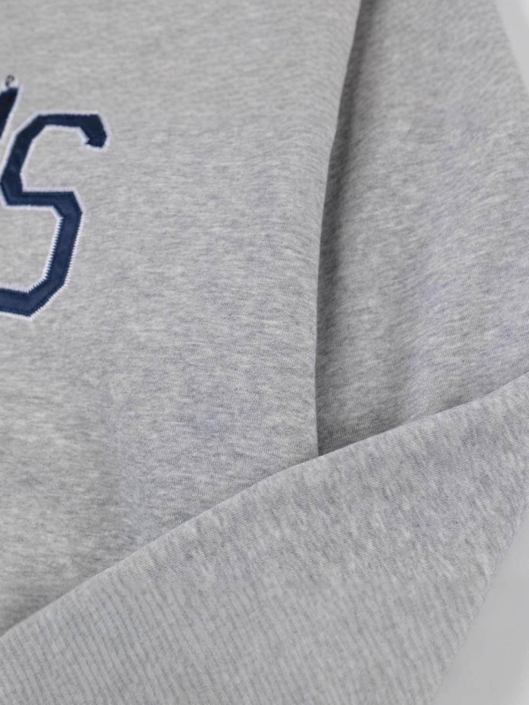 A close-up of the gray TALISHKO hoodie, focusing on its minimalistic letter design and soft texture.