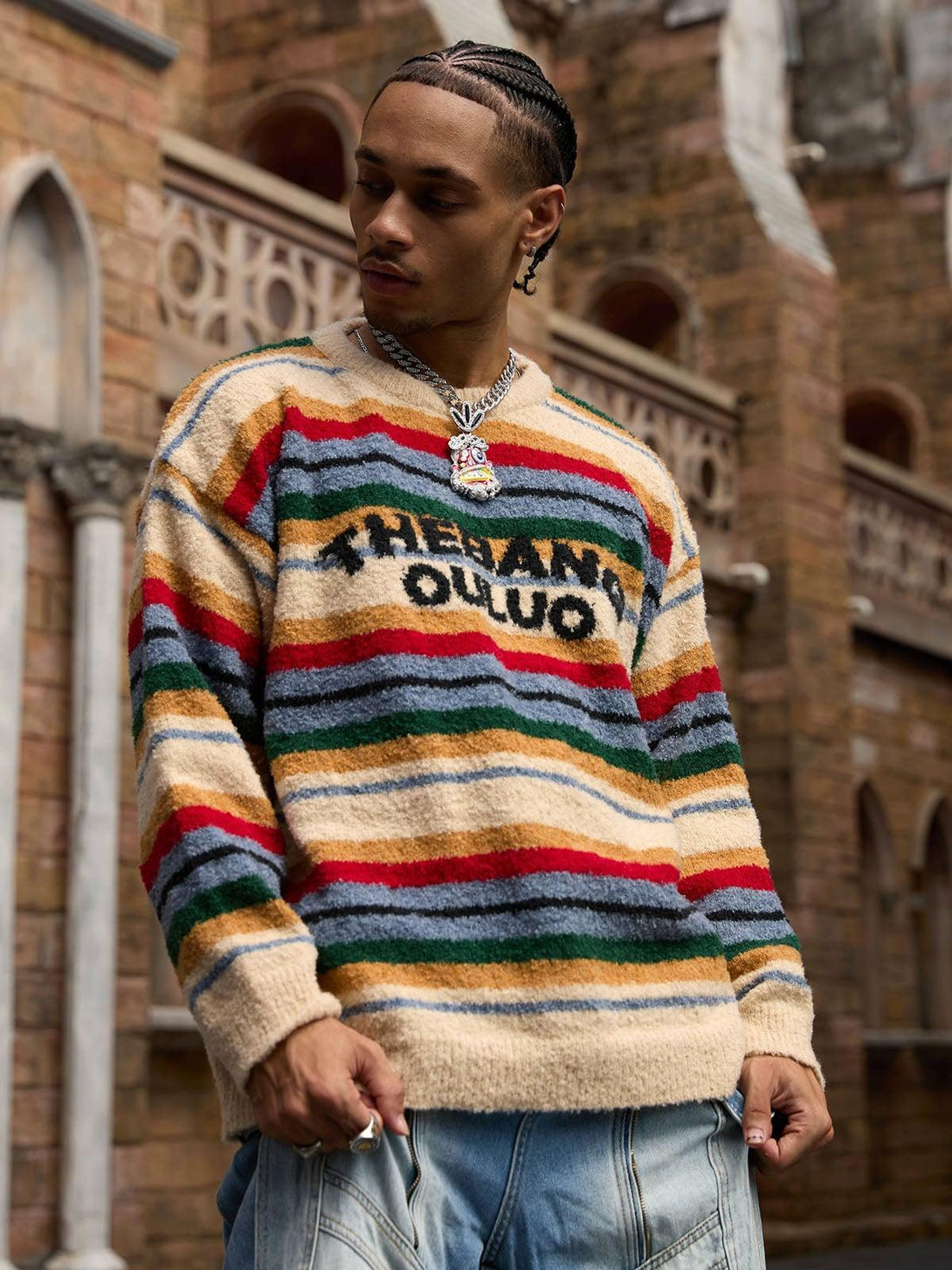 Model styled in a vibrant striped sweater by TALISHKO, showcasing bold lettering in an urban setting.