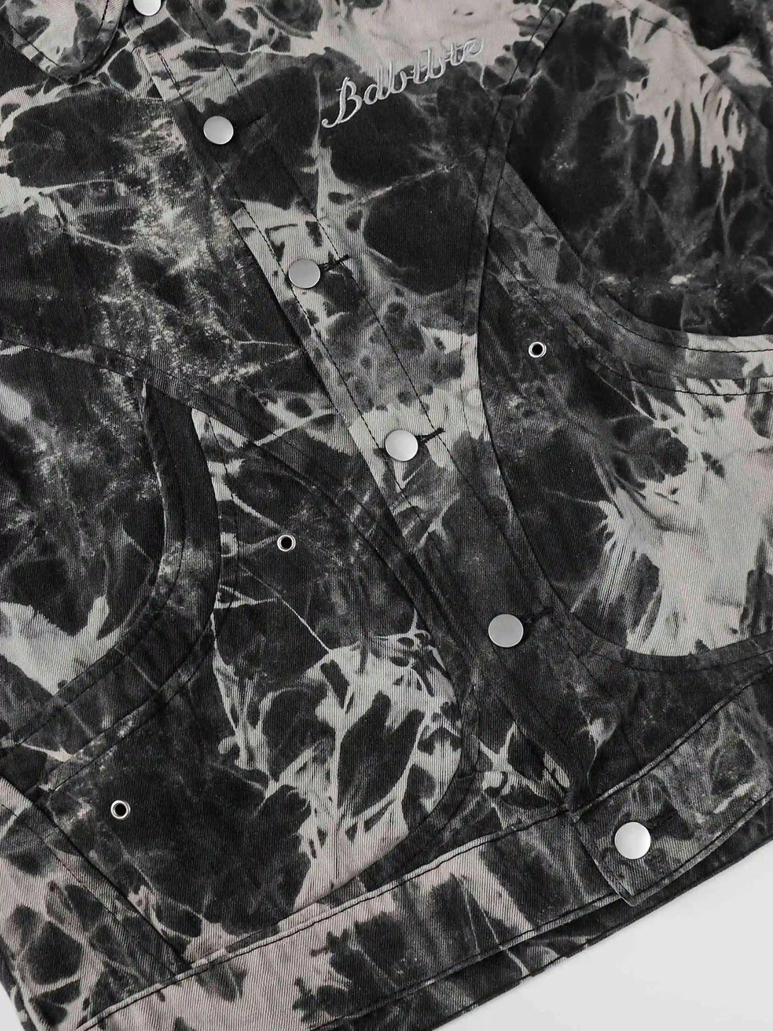 Focusing on the button details of TALISHKO's vintage tie-dye denim jacket, highlighting its edgy style.