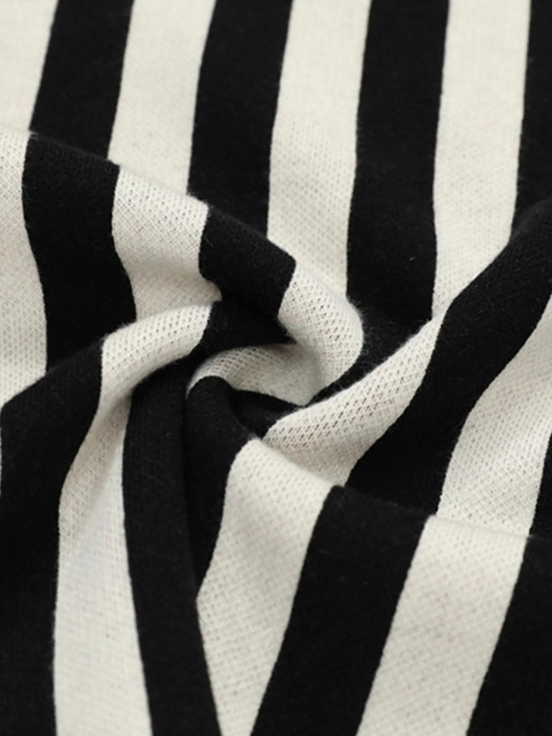 A zoomed-in texture of black and white stripes on a V-neck sweater by TALISHKO, highlighting preppy style.