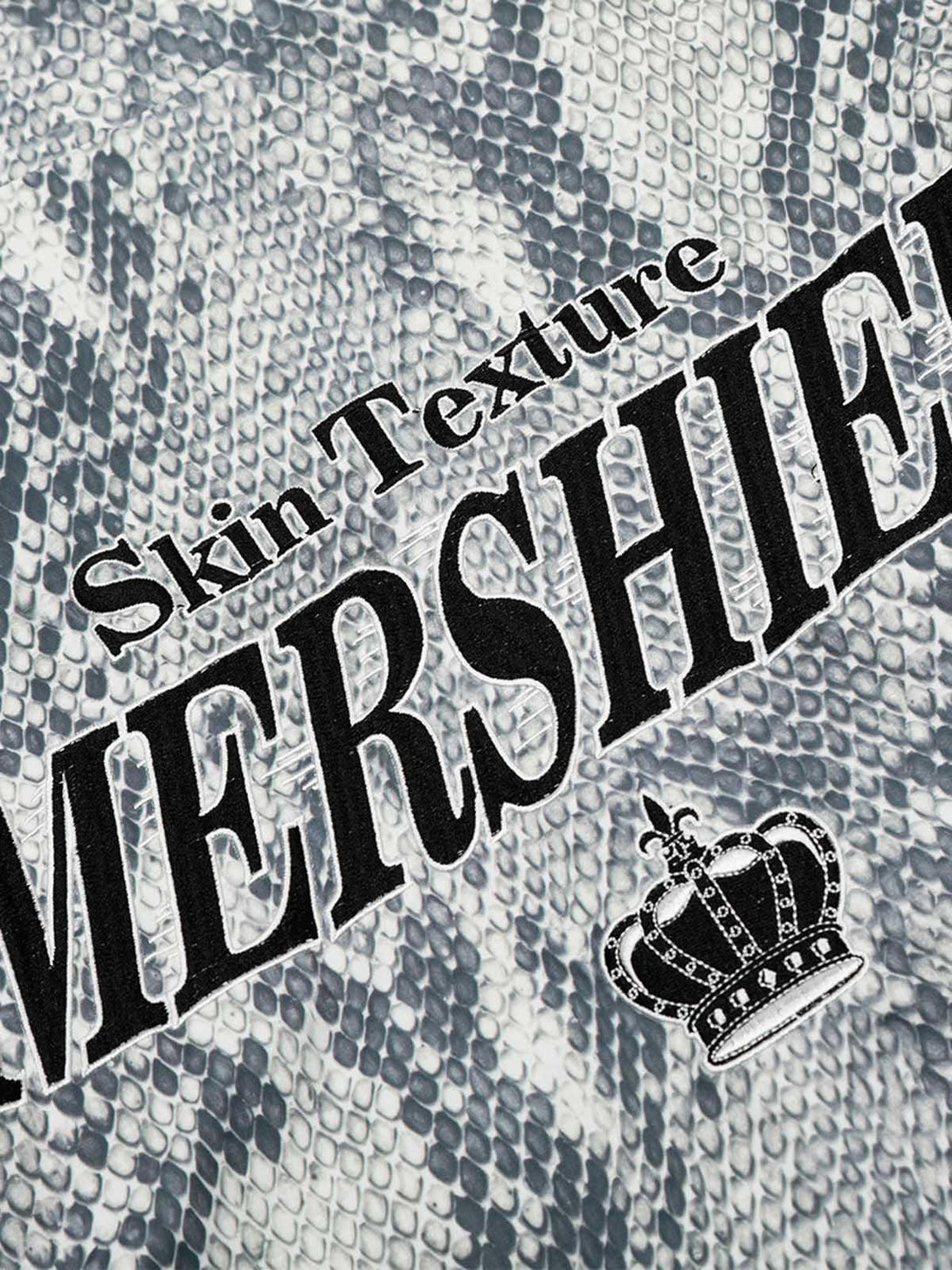Zoomed-in texture of the TALISHKO windbreaker jacket, featuring a gray snakeskin pattern.