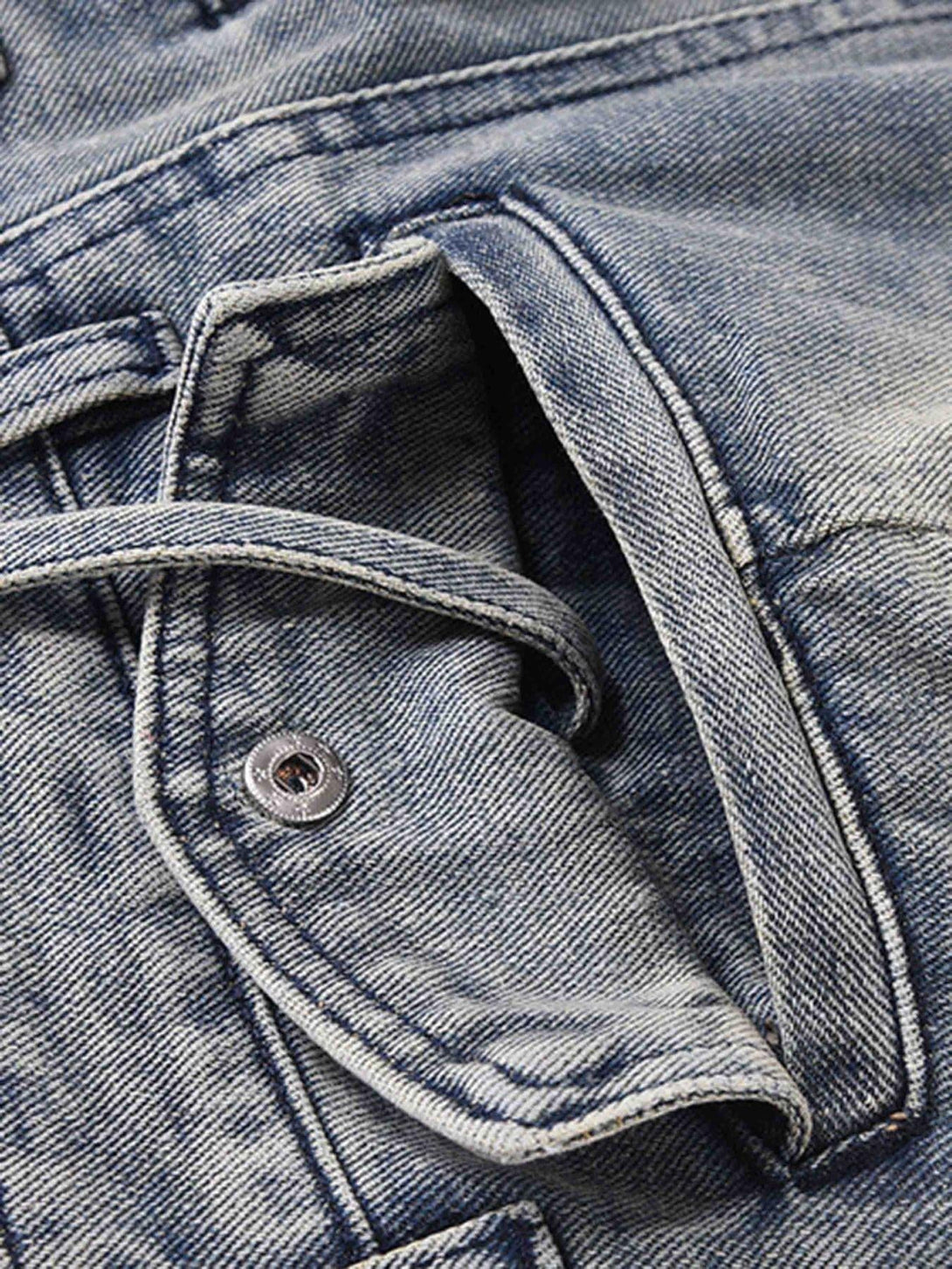 Detailed look at TALISHKO's vintage washed jeans, focusing on button closure and stitching.