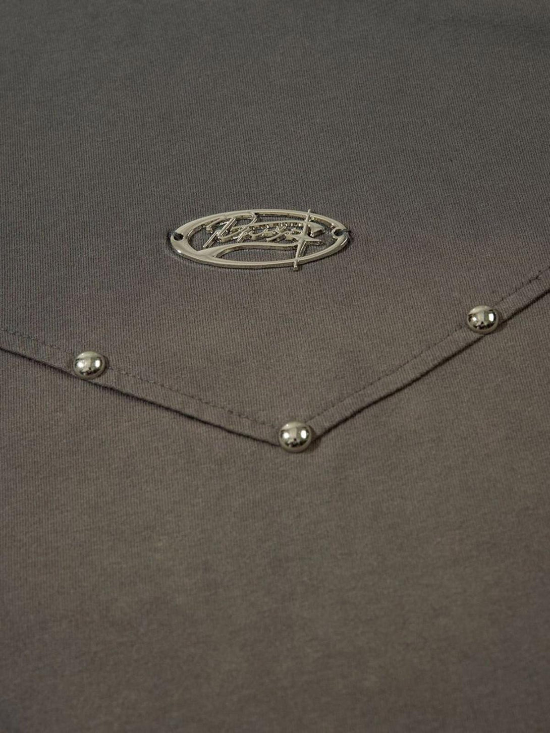 Intricate look at rivet accents and logo detail on a gray T-shirt by TALISHKO.